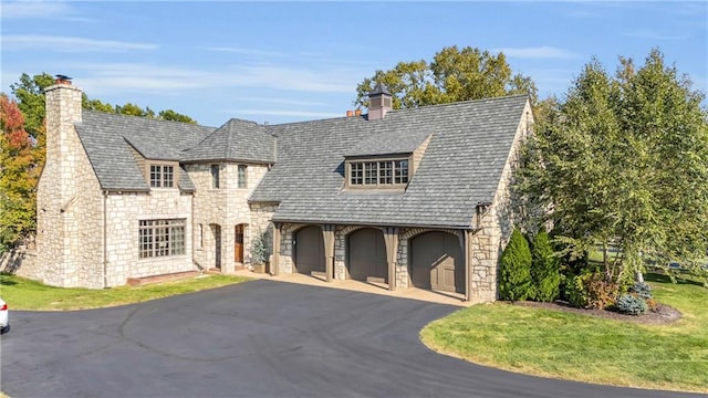 10400 Howe Dr, Leawood, KS 66206 - view of front facade featuring stone siding, a chimney, asphalt driveway, an attached garage, and a front lawn