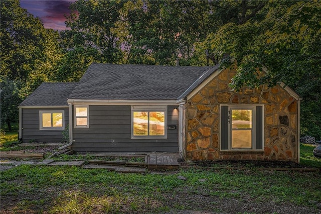 707 N Forest Ave, Independence, MO 64050 - view of front of home with stone siding, roof with shingles, and a yard