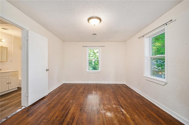 707 N Forest Ave, Independence, MO 64050 - empty room featuring dark wood-style flooring, plenty of natural light, and a textured ceiling
