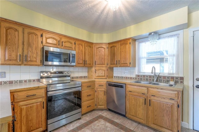 2508 N Mcbride Ave, Sugar Creek, MO 64050 - kitchen with appliances with stainless steel finishes, light countertops, backsplash, brown cabinetry, and a textured ceiling