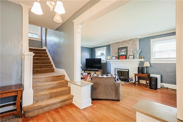 2517 Felix St, Saint Joseph, MO 64501 - living area with light wood-style flooring, stairs, a fireplace, a textured wall, and crown molding