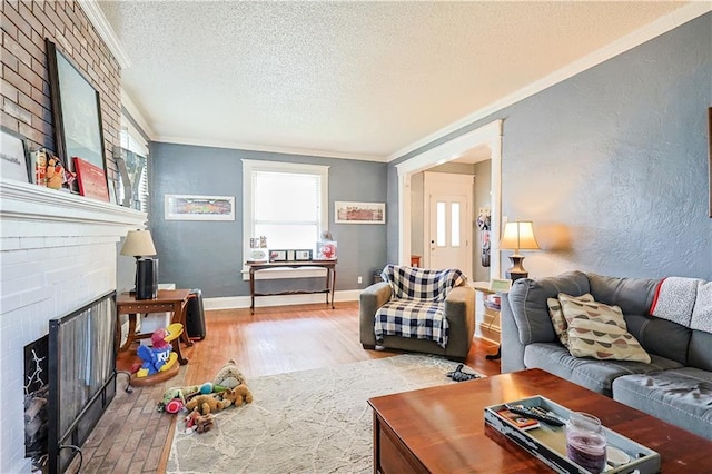 2517 Felix St, Saint Joseph, MO 64501 - living room with a brick fireplace, crown molding, a textured ceiling, plenty of natural light, and wood finished floors