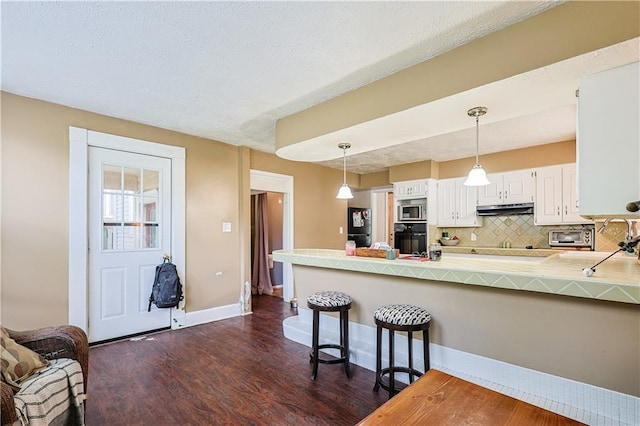 2517 Felix St, Saint Joseph, MO 64501 - kitchen with black appliances, dark wood-type flooring, a peninsula, tasteful backsplash, and under cabinet range hood