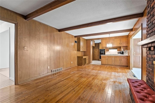 3300 W 93rd St, Leawood, KS 66206 - unfurnished living room with beamed ceiling, light wood-style floors, wood walls, and a brick fireplace