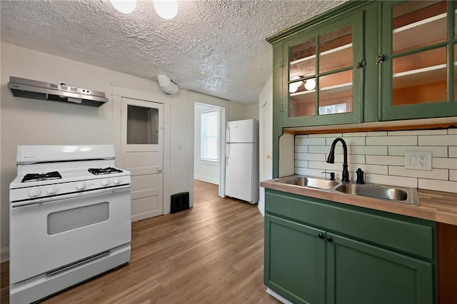 422 N Thompson St, Kansas City, KS 66101 - kitchen featuring white appliances, green cabinets, under cabinet range hood, light wood-type flooring, and decorative backsplash