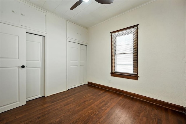 422 N Thompson St, Kansas City, KS 66101 - unfurnished bedroom featuring dark wood-style floors, ornamental molding, a ceiling fan, and multiple closets
