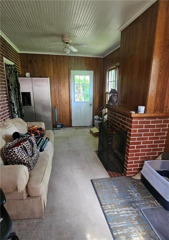 2003 S Elm St, Pittsburg, KS 66762 - living area with ceiling fan, a brick fireplace, wooden walls, crown molding, and brick wall