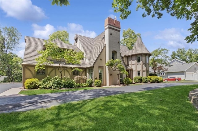8320 Maplewood Ln, Lenexa, KS 66215 - tudor house featuring stucco siding, a front yard, and a chimney