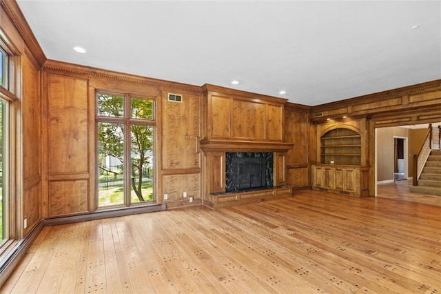 8320 Maplewood Ln, Lenexa, KS 66215 - unfurnished living room with wood walls, stairway, light wood finished floors, crown molding, and a high end fireplace