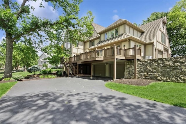 8320 Maplewood Ln, Lenexa, KS 66215 - view of front facade with a garage, driveway, stucco siding, stairs, and a deck