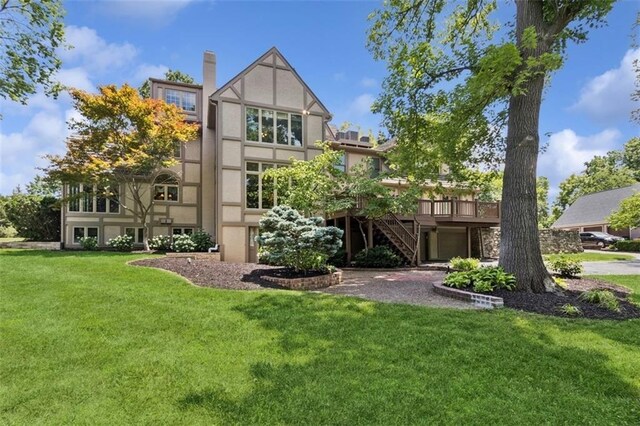 8320 Maplewood Ln, Lenexa, KS 66215 - rear view of property with stairway, a wooden deck, a lawn, and stucco siding