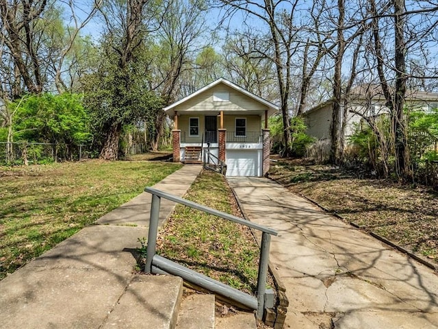 3928 E 58th St, Kansas City, MO 64132 - bungalow with a porch, driveway, brick siding, and an attached garage