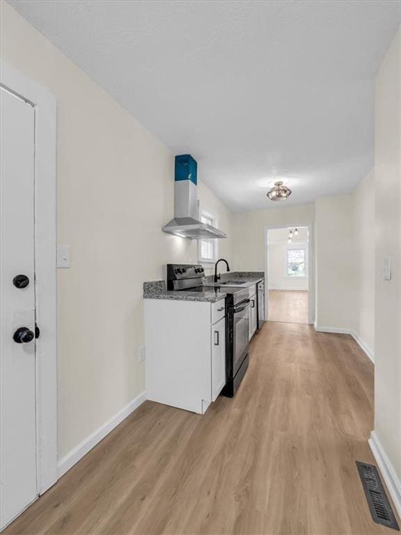 3928 E 58th St, Kansas City, MO 64132 - kitchen with black range with electric cooktop, wall chimney exhaust hood, light wood-type flooring, and white cabinets