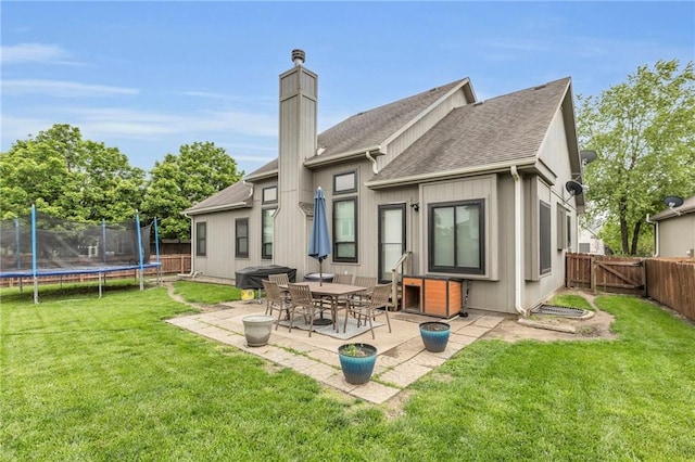 23968 Eagle Ct, Paola, KS 66071 - rear view of house with a patio, a fenced backyard, a trampoline, and roof with shingles