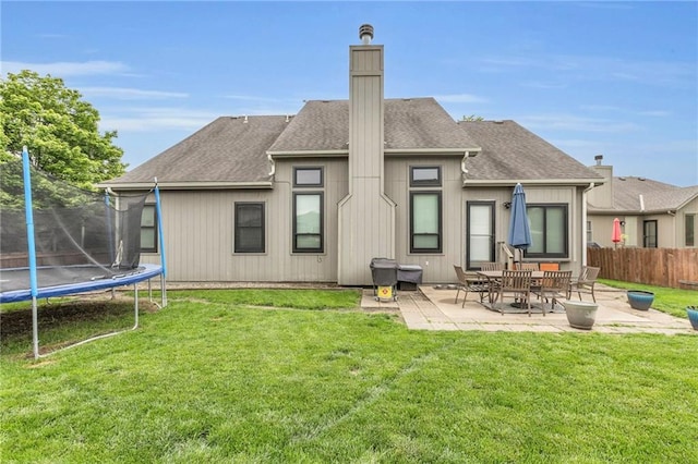 23968 Eagle Ct, Paola, KS 66071 - rear view of property featuring a trampoline, a patio area, a chimney, and a shingled roof