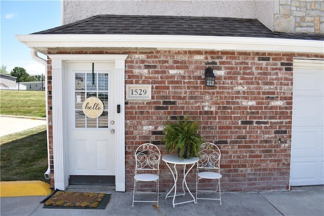 1529 E 120th St, Olathe, KS 66061 - view of exterior entry featuring a garage, brick siding, and a shingled roof