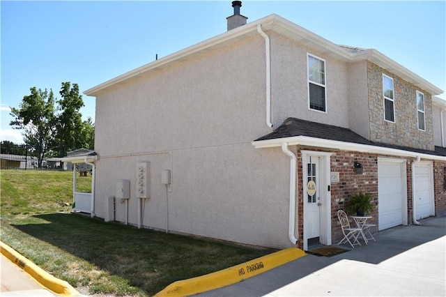 1529 E 120th St, Olathe, KS 66061 - view of home's exterior featuring stucco siding, a lawn, a chimney, driveway, and an attached garage