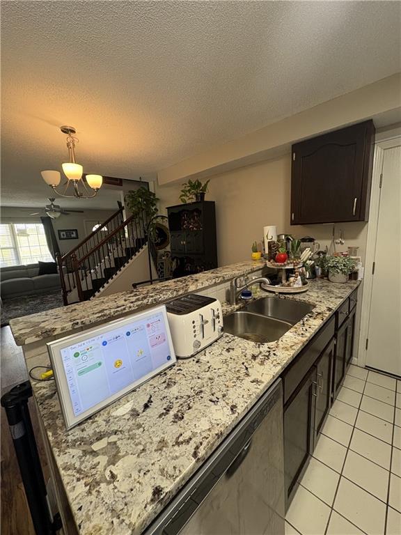 1529 E 120th St, Olathe, KS 66061 - kitchen featuring a textured ceiling, a chandelier, light tile patterned flooring, a peninsula, and light stone counters