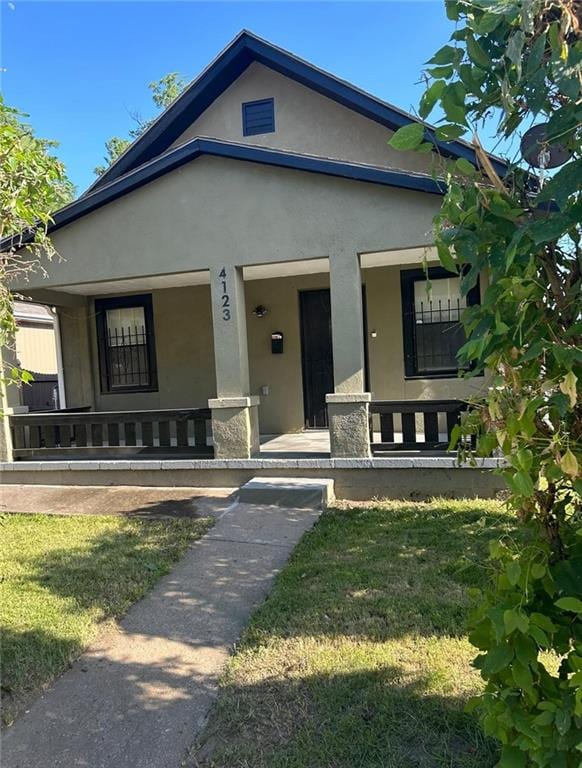 4123 E 6th St, Kansas City, MO 64124 - bungalow with a porch, stucco siding, and a front lawn