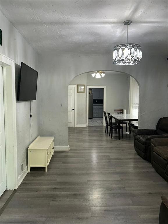 4123 E 6th St, Kansas City, MO 64124 - living area with arched walkways, dark wood-style flooring, and a chandelier