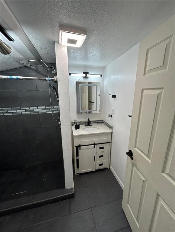 4123 E 6th St, Kansas City, MO 64124 - bathroom featuring vanity, a stall shower, tile patterned flooring, and a textured ceiling