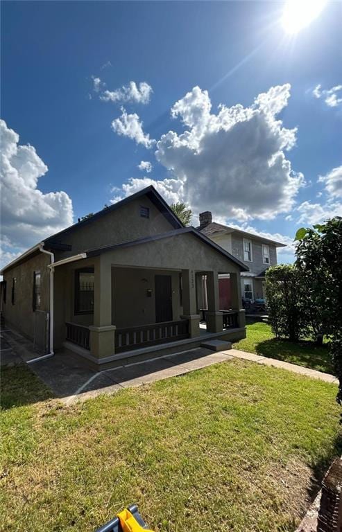 4123 E 6th St, Kansas City, MO 64124 - back of property featuring stucco siding, a yard, and a porch