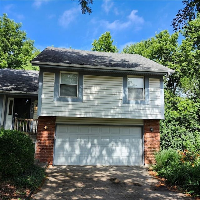 9318 Greenway Ln, Lenexa, KS 66215 - split level home with brick siding, an attached garage, driveway, and roof with shingles