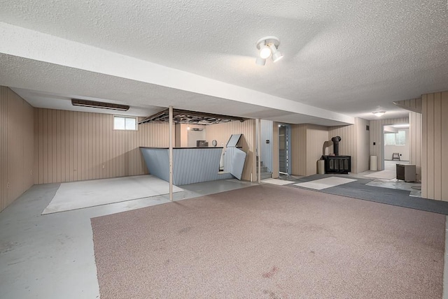20723 Kissinger Rd, Tonganoxie, KS 66086 - basement featuring a wood stove, a textured ceiling, stairs, healthy amount of natural light, and wooden walls