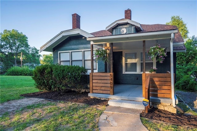 5409 Brooklyn Ave, Kansas City, MO 64130 - view of front of home featuring a chimney, a front yard, and covered porch
