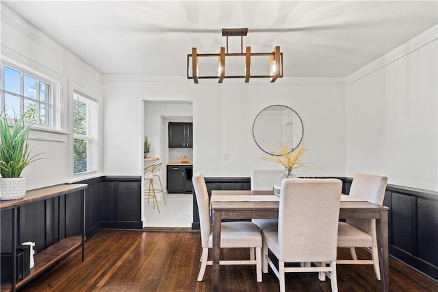 5409 Brooklyn Ave, Kansas City, MO 64130 - dining room with wood finished floors, a chandelier, a wainscoted wall, and ornamental molding
