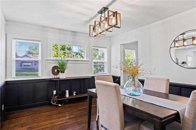5409 Brooklyn Ave, Kansas City, MO 64130 - dining room featuring wood finished floors, ornamental molding, wainscoting, a decorative wall, and a chandelier