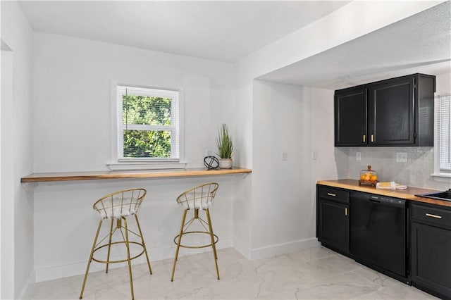 5409 Brooklyn Ave, Kansas City, MO 64130 - kitchen with dishwasher, dark cabinetry, light marble finish floors, tasteful backsplash, and a breakfast bar
