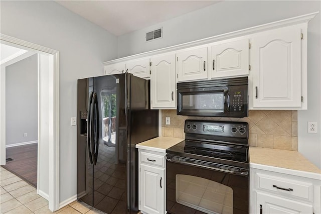 701 Redbud Dr, Paola, KS 66071 - kitchen with black appliances, light countertops, light tile patterned floors, and white cabinets