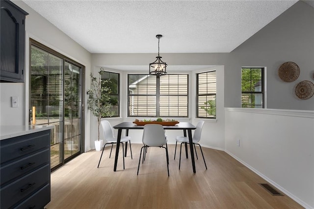 404 SE Bristol Dr, Lees Summit, MO 64063 - dining area with a textured ceiling, light wood-type flooring, healthy amount of natural light, and a chandelier