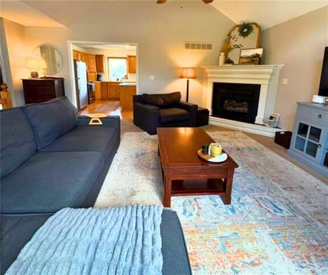 1720 SE Kenwood Dr, Blue Springs, MO 64014 - living area with vaulted ceiling, a ceiling fan, and a fireplace with raised hearth