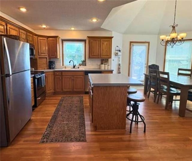 1720 SE Kenwood Dr, Blue Springs, MO 64014 - kitchen featuring appliances with stainless steel finishes, a chandelier, a kitchen island, wood finished floors, and a breakfast bar