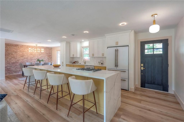 9730 State Line Rd, Leawood, KS 66206 - kitchen featuring high end fridge, brick wall, a spacious island, white cabinets, and a chandelier
