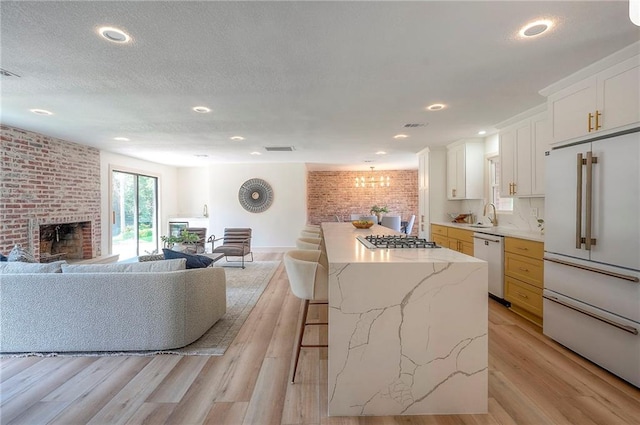 9730 State Line Rd, Leawood, KS 66206 - kitchen with appliances with stainless steel finishes, a breakfast bar, a brick fireplace, open floor plan, and brick wall
