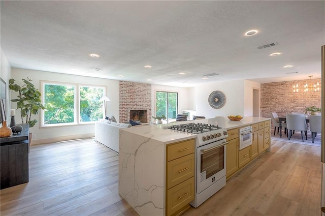 9730 State Line Rd, Leawood, KS 66206 - kitchen with white range with gas stovetop, a fireplace, open floor plan, light wood-style flooring, and recessed lighting