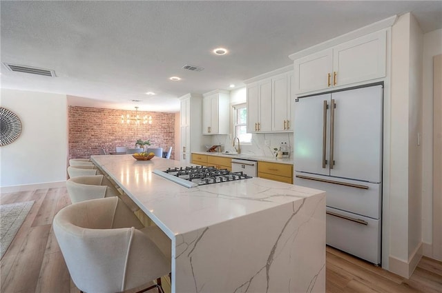 9730 State Line Rd, Leawood, KS 66206 - kitchen featuring high end fridge, stainless steel gas cooktop, a center island, a chandelier, and light wood-type flooring