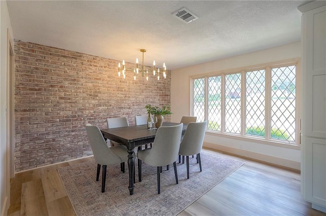 9730 State Line Rd, Leawood, KS 66206 - dining space featuring a textured ceiling, light wood-type flooring, a chandelier, and brick wall