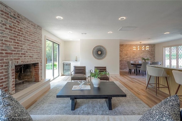 9730 State Line Rd, Leawood, KS 66206 - living room featuring wine cooler, a chandelier, a fireplace, light wood-style flooring, and brick wall