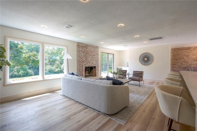 9730 State Line Rd, Leawood, KS 66206 - living area featuring a brick fireplace, a textured ceiling, light wood-type flooring, and recessed lighting