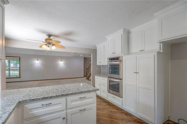 11512 Hadley St, Overland Park, KS 66210 - kitchen featuring double oven, a ceiling fan, white cabinets, a textured ceiling, and dark wood-type flooring