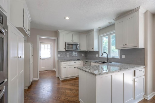 11512 Hadley St, Overland Park, KS 66210 - kitchen featuring stainless steel appliances, a peninsula, white cabinetry, tasteful backsplash, and recessed lighting