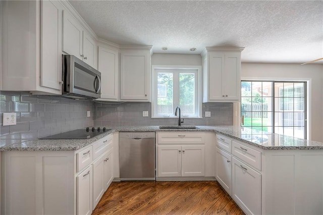 11512 Hadley St, Overland Park, KS 66210 - kitchen featuring stainless steel appliances, a peninsula, wood finished floors, white cabinets, and a textured ceiling