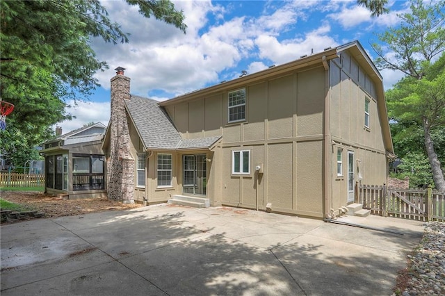11512 Hadley St, Overland Park, KS 66210 - rear view of house featuring a patio area, a chimney, board and batten siding, and a sunroom