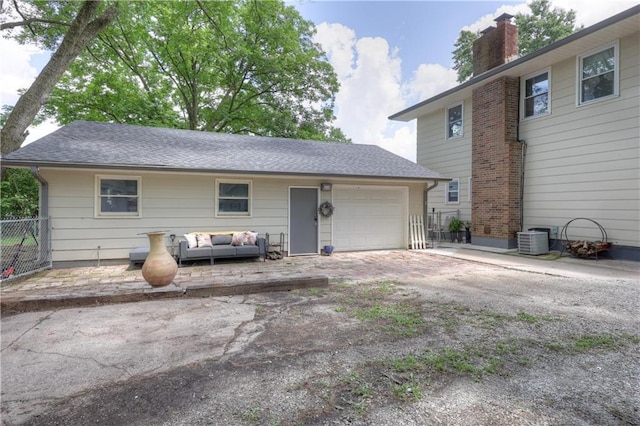2509 E 4th St, Pittsburg, KS 66762 - rear view of property featuring a garage, a chimney, dirt driveway, and an outdoor hangout area