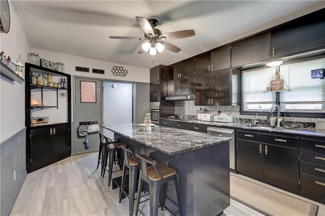 2509 E 4th St, Pittsburg, KS 66762 - kitchen featuring a kitchen bar, stainless steel dishwasher, a ceiling fan, a center island, and dark stone counters
