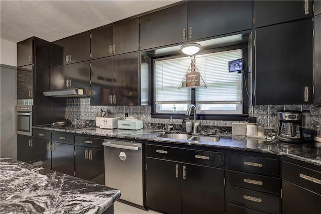 2509 E 4th St, Pittsburg, KS 66762 - kitchen featuring appliances with stainless steel finishes, tasteful backsplash, dark stone countertops, under cabinet range hood, and a textured ceiling